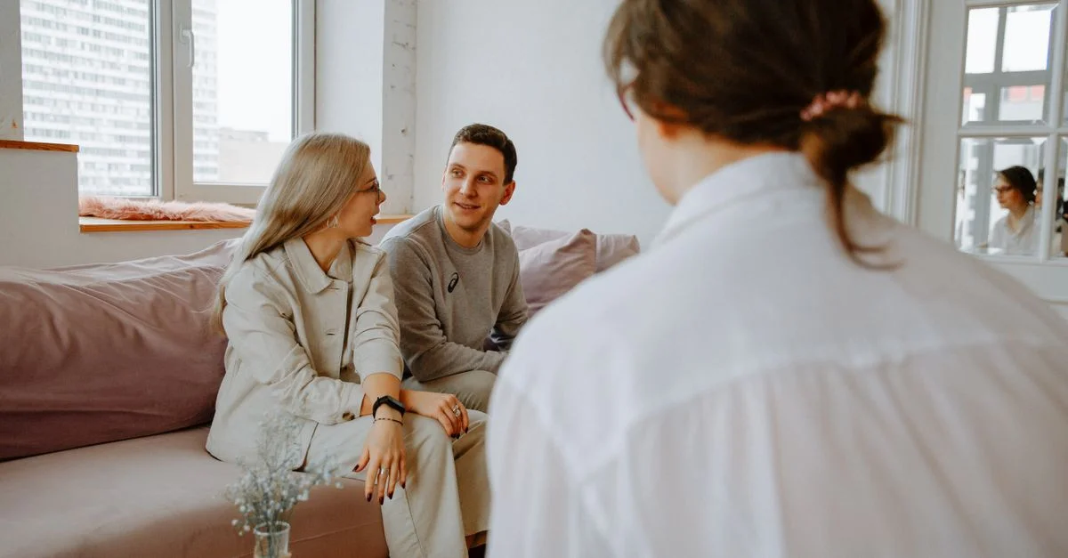 Un couple engagé dans une séance de counseling avec un thérapeute dans un cadre intérieur moderne.