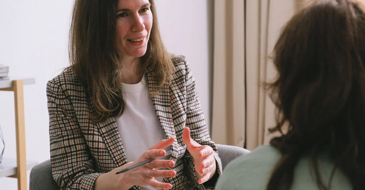 Une thérapeute féminine écoute attentivement et engage la discussion lors d'une séance de thérapie à l'intérieur.