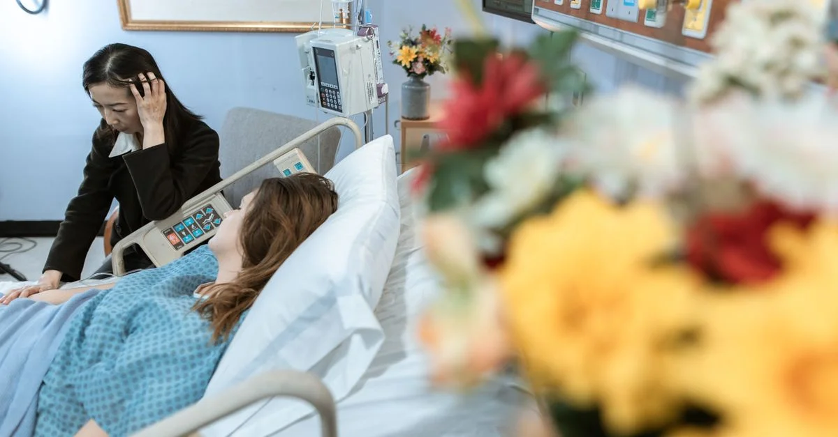 Femme rendant visite à un patient dans une chambre d'hôpital, montrant soin et confort.