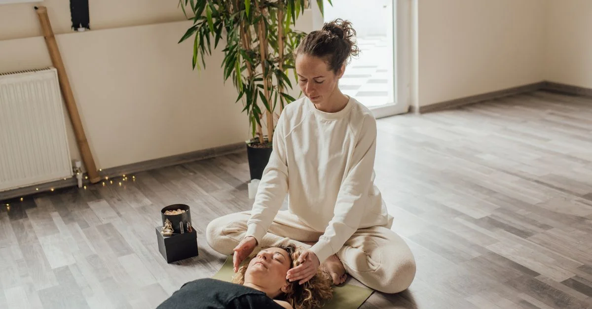 Une séance de Reiki apaisante à l'intérieur avec un thérapeute et un patient sur un tapis de yoga, axée sur l'énergie de guérison.