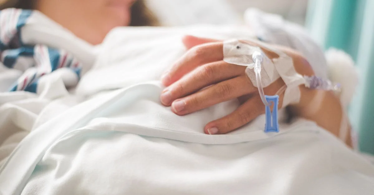 Plan rapproché de la main d'un patient avec un IV dans un cadre hospitalier.